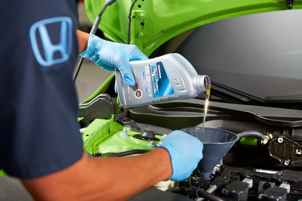 Honda Technician replacing car engine oil